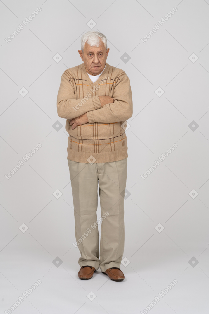 Вид спереди на старика в повседневной одежде, стоящего со скрещенными руками и смотрящего в камеру