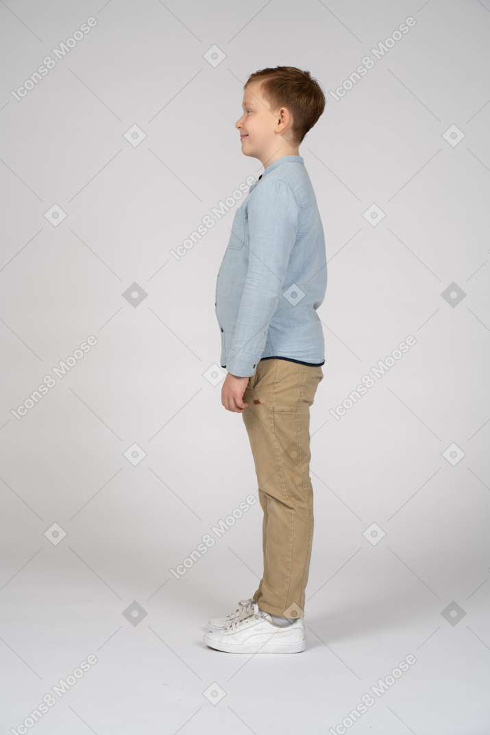 Happy boy in casual clothes standing in profile