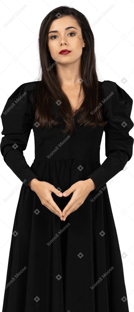 Vista frontale di una giovane donna prepotente in un vestito nero che tengono le mani insieme