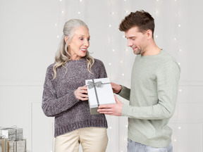 A man giving a christmas present to an old woman