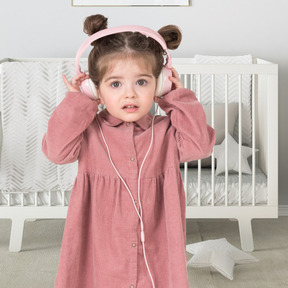 A little girl wearing headphones and a pink dress