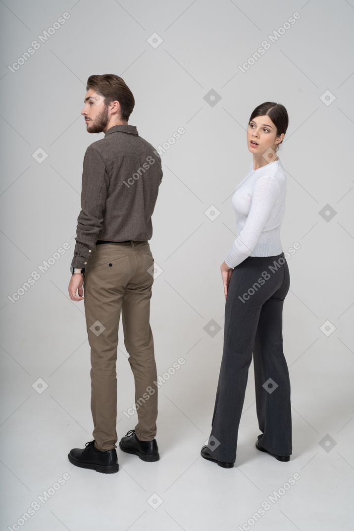 Vista posteriore di tre quarti di una giovane coppia curiosa in abiti da ufficio