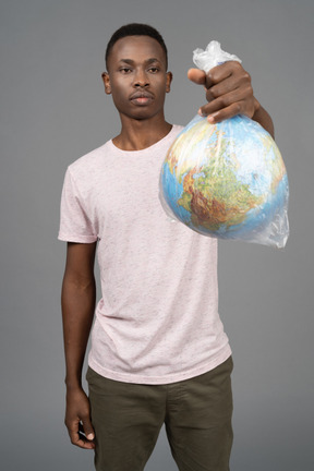 A young man holding a white plastic with the earth globe