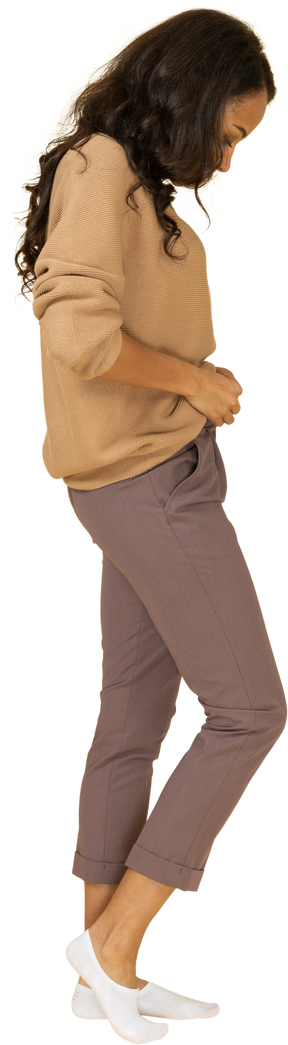 Vista lateral de una mujer joven de piel oscura subiendo la cremallera de sus pantalones