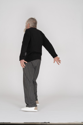Elderly man standing with his arms extended backwards