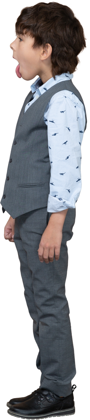Side view of a boy in grey suit showing tongue