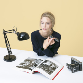 Jeune femme assise à la table et tenant ses lunettes de vue