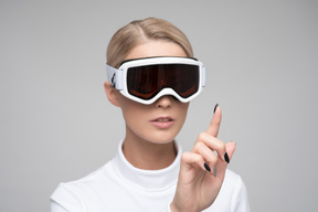 Woman in ski goggles touching something virtual