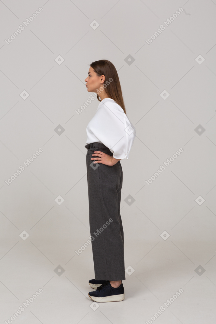 Side view of a young lady in office clothing putting hands on hips