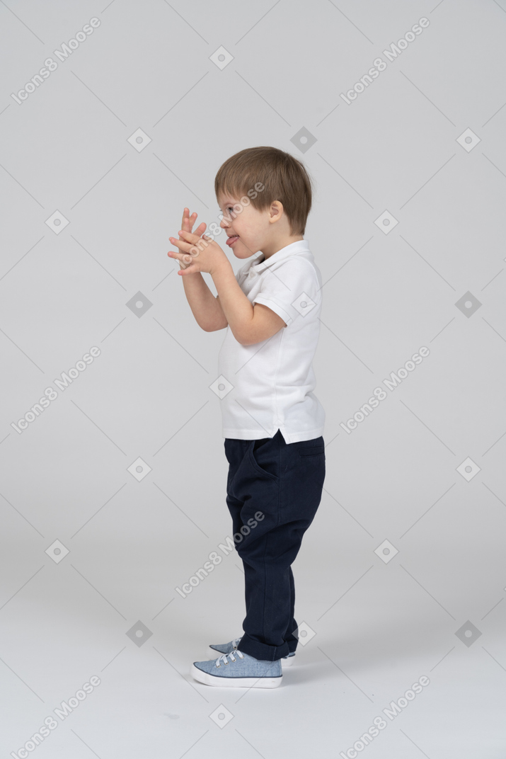 Вид сбоку маленького мальчика, корчащего рожи