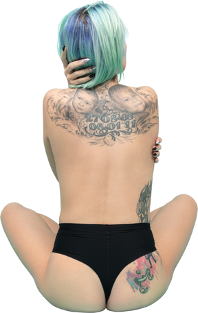 Tattooed woman in black bikini sitting back to camera
