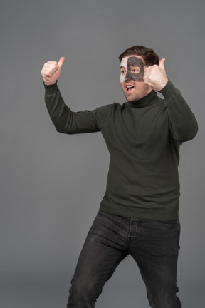 Three-quarter view of a cheerful male football fan showing thumbs up