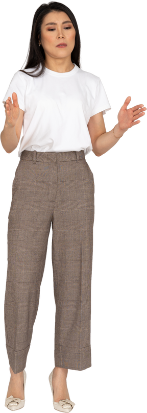 Vista frontal de uma jovem de calça e camiseta branca mostrando o tamanho de alguma coisa