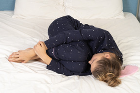 Ganzkörperansicht einer jungen dame im schlafanzug, die im bett liegt