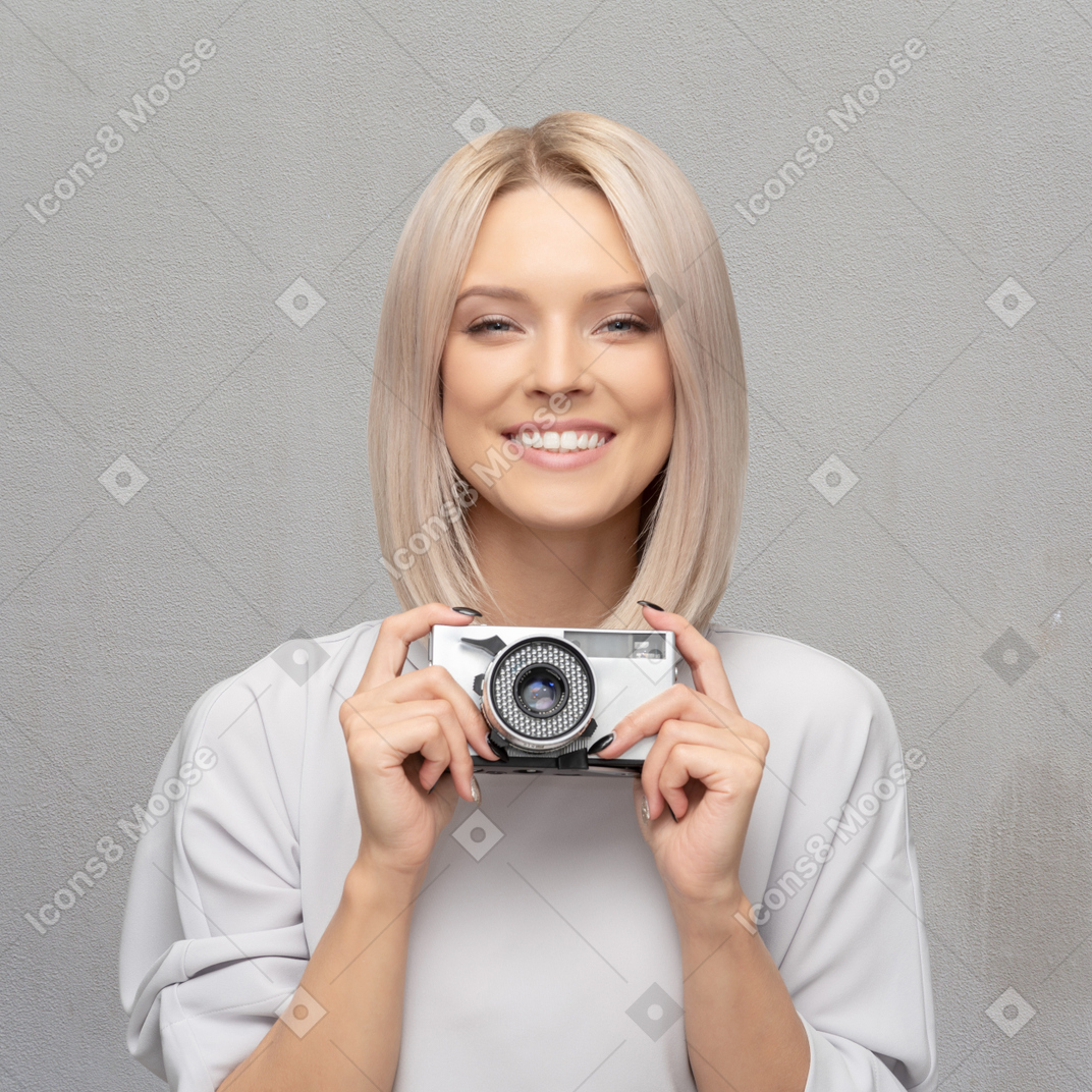 Giovane donna allegra che tiene macchina fotografica d'epoca