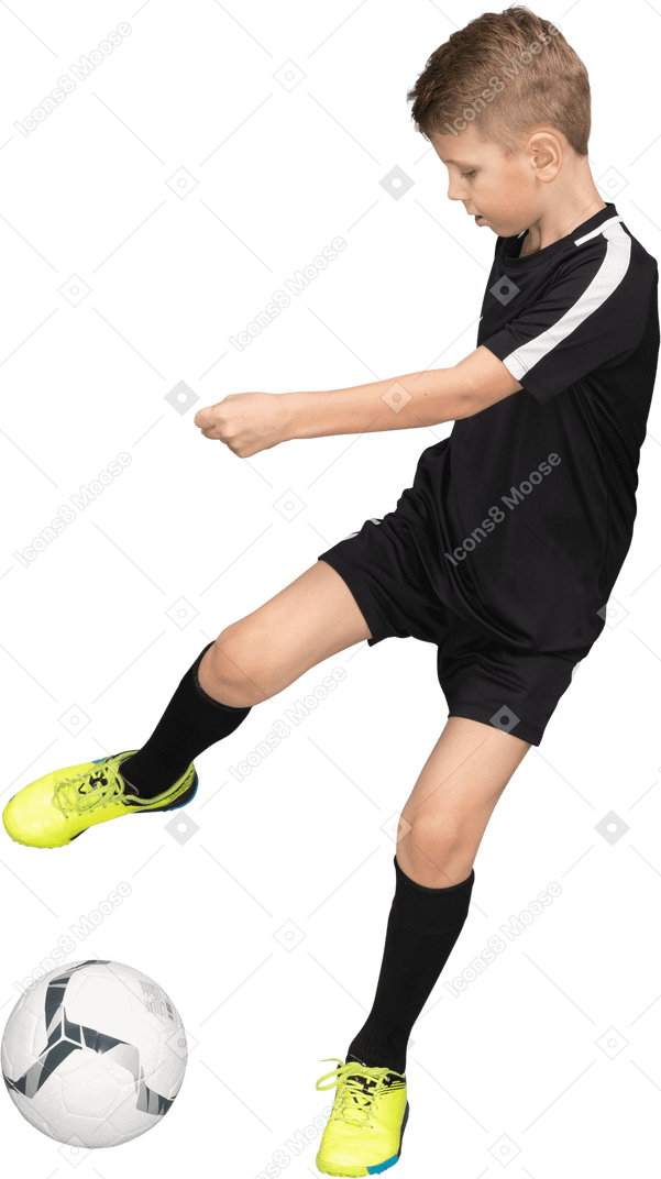 Vista frontal de un niño niño en uniforme de fútbol pateando una pelota