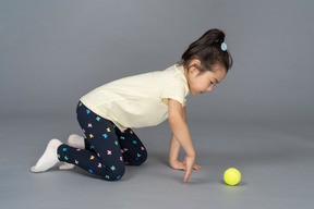 Niña a cuatro patas jugando con una pelota de tenis