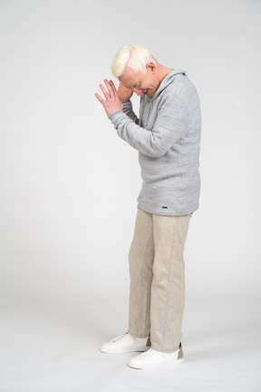 Hombre de mediana edad de pie y cubriendo su rostro