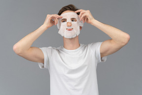 Vista frontal de um jovem colocando máscara facial