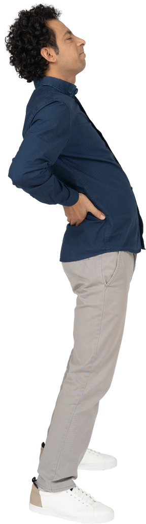 Vista laterale di un uomo in abiti casual che soffre di dolore nella parte bassa della schiena