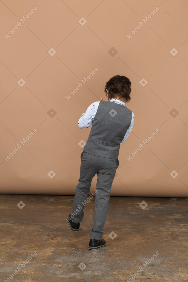 Vista posteriore di un ragazzo in tuta che dà dei calci a qualcosa