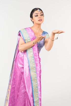 Young indian woman in purple sari standing with hands folded