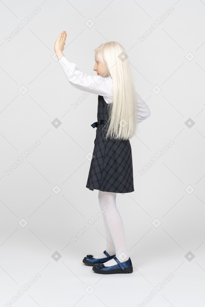Вид сбоку на школьницу, поднимающую руку