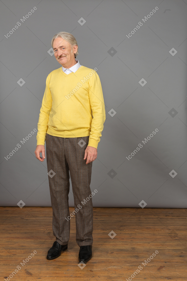 一个微笑的老人，穿着黄色套头衫，看着相机的前视图