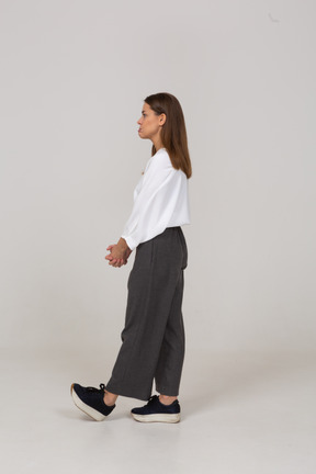 Side view of a displeased young lady in office clothing holding hands together