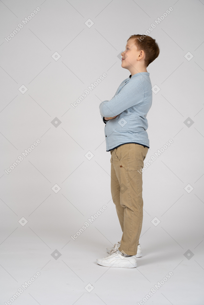 Boy posing with crossed arms and looking up