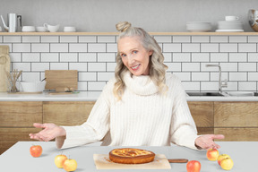 A woman sitting at a table with an apple pie in front of her