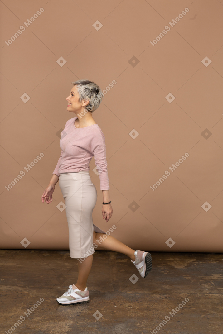 Side view of a happy woman in casual clothes standing on one leg