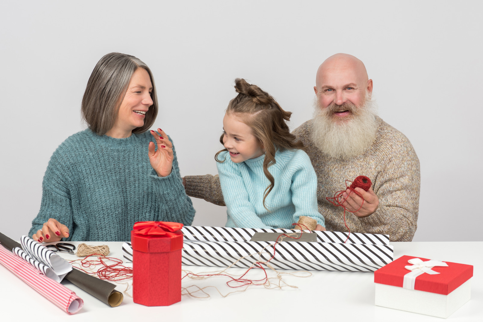 Smiling grandparents and granddaughter wrapping christmas presents