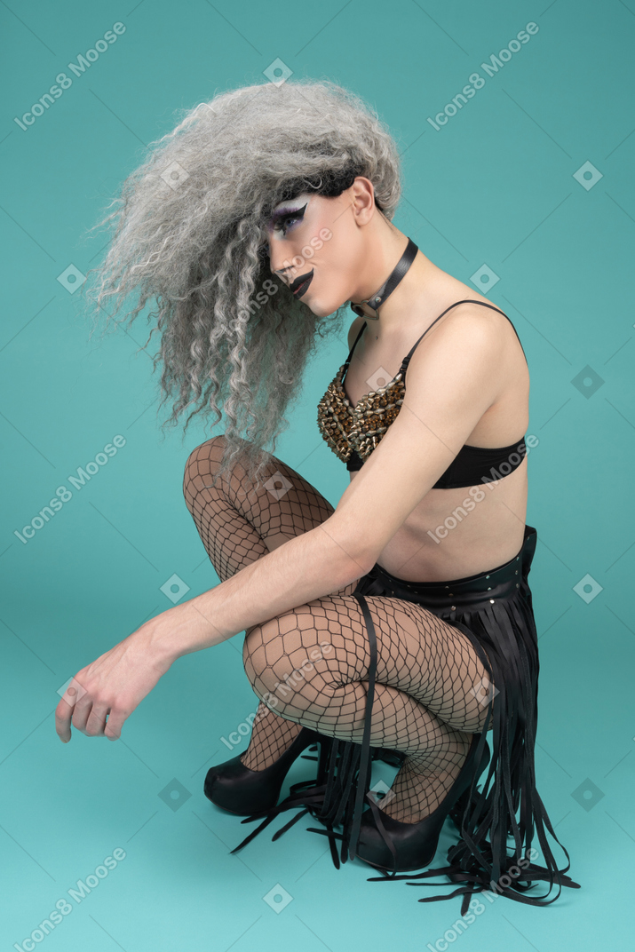 Drag queen squatting with hair covering their face