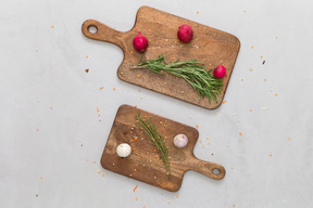 Red radishes, garlic and herbs served on wooden cutting boards