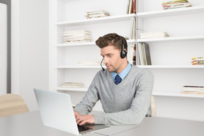 A man sitting at a desk using a laptop computer