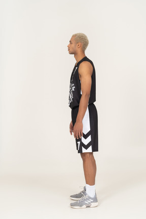 Vista lateral de um jovem jogador de basquete parado
