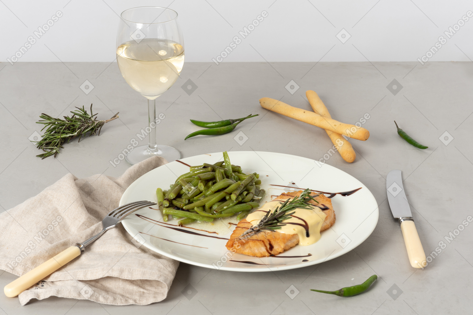Plato de pescado y judías verdes, copa de vino blanco, grissini, tenedor y cuchillo