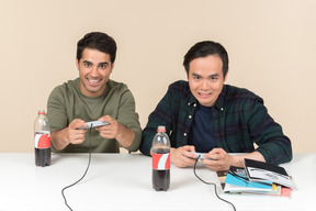 Interracial friends sitting at the table and playing video game