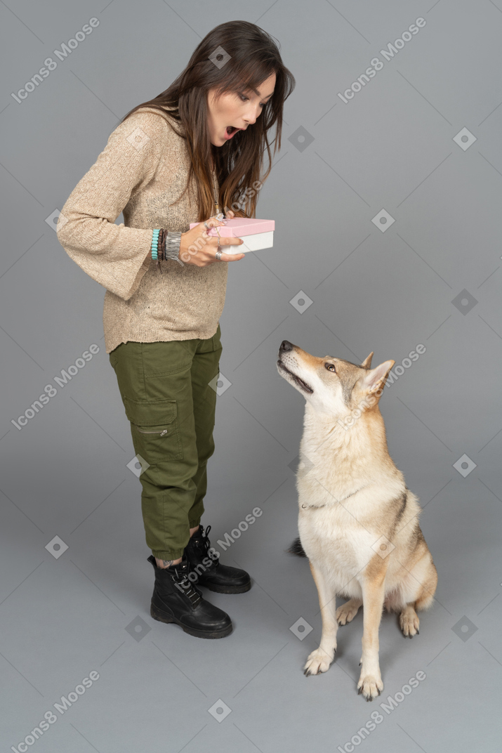 Surprised young woman opening a box