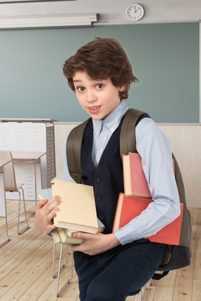 A boy holding books in a classroom