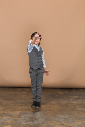 Vista frontal de un niño con traje gris que muestra un gesto de parada