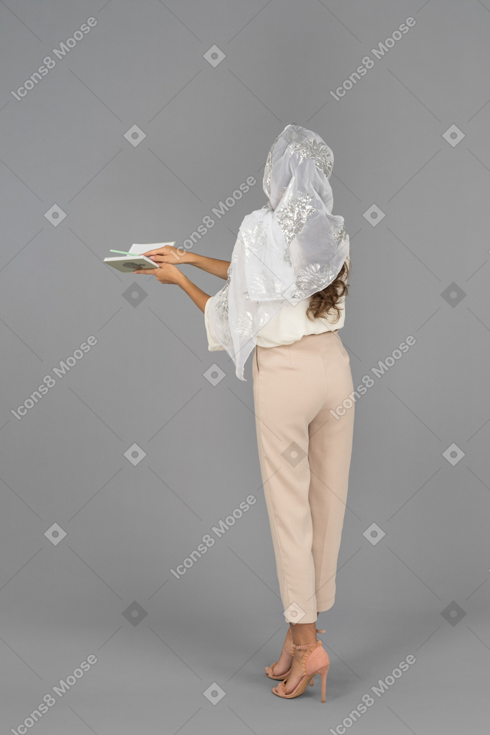 Unrecognizable woman n white shawl holding a notebook