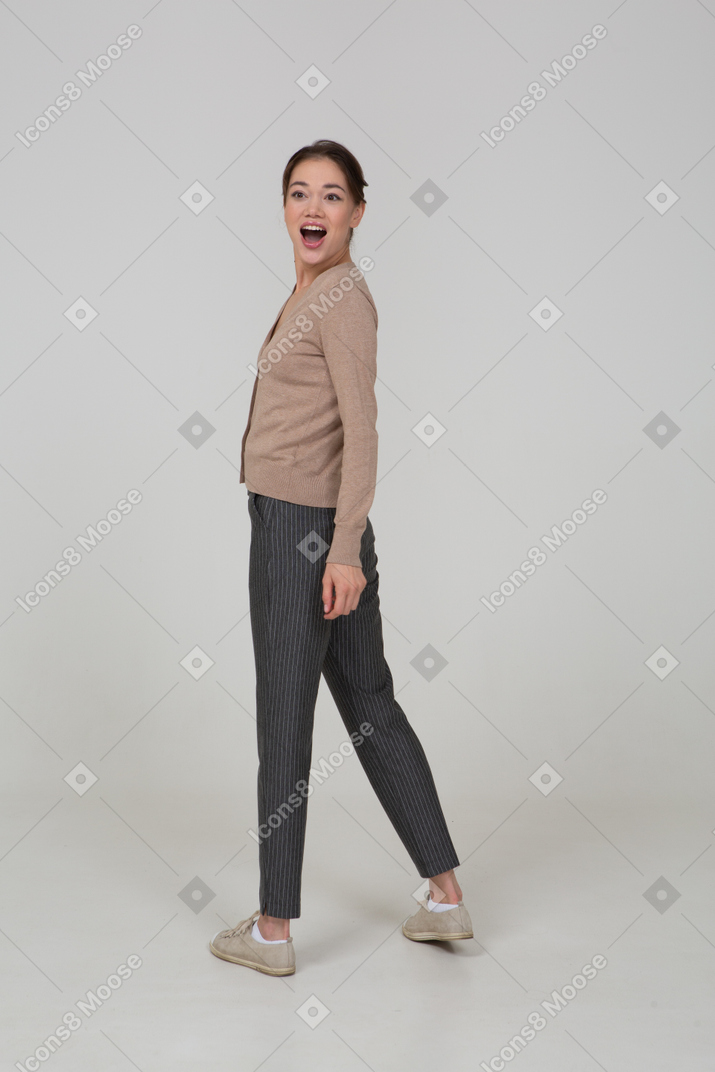 Vista posteriore di tre quarti di una donna sorridente sorpresa in pullover beige voltare le spalle