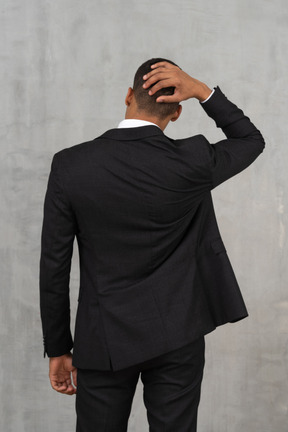 黒のスーツを着た若い男の背面図