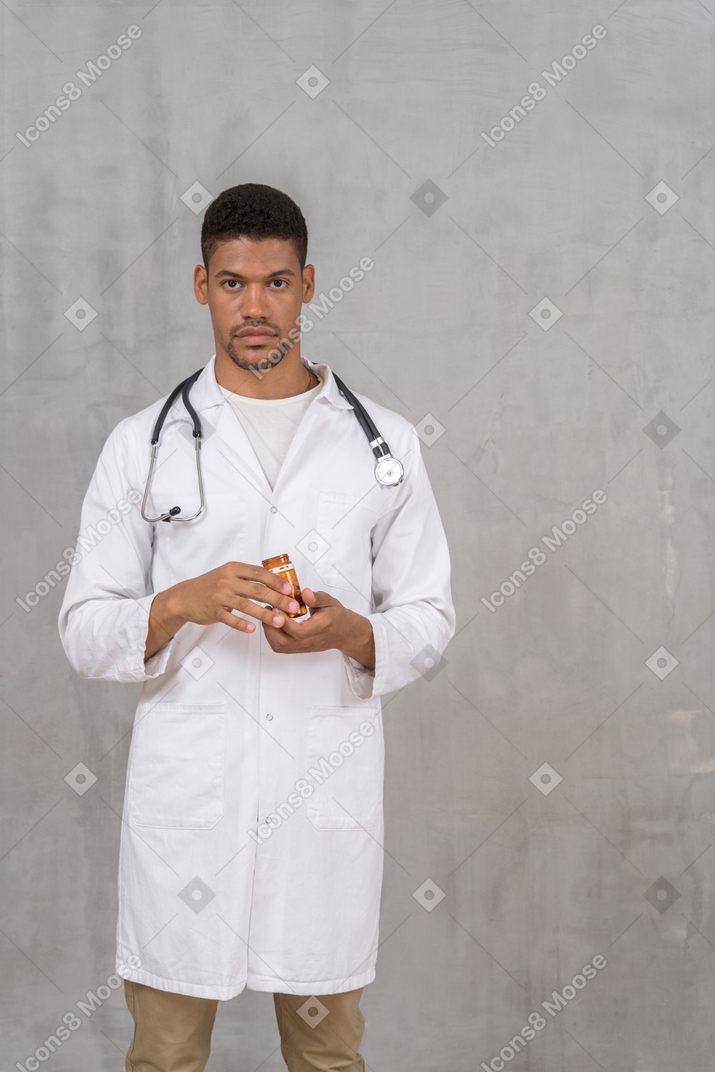 Giovane medico che tiene una bottiglia di pillole