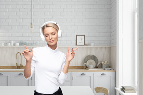 A woman wearing headphones standing in a kitchen