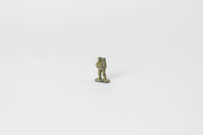 A miniature toy soldier standing in the middle of the picture against a plain white background