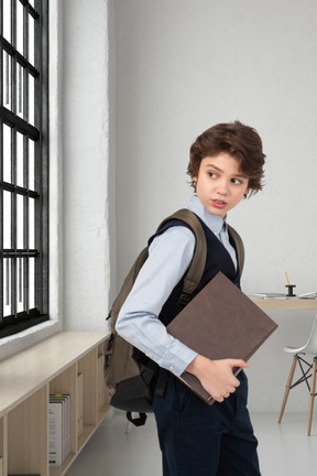 A schoolboy holding a book in a class