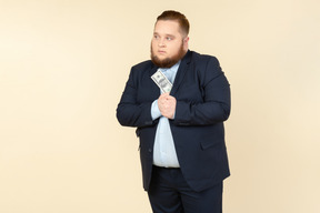 A plus-size man in a black costume with dollar bills in his hands